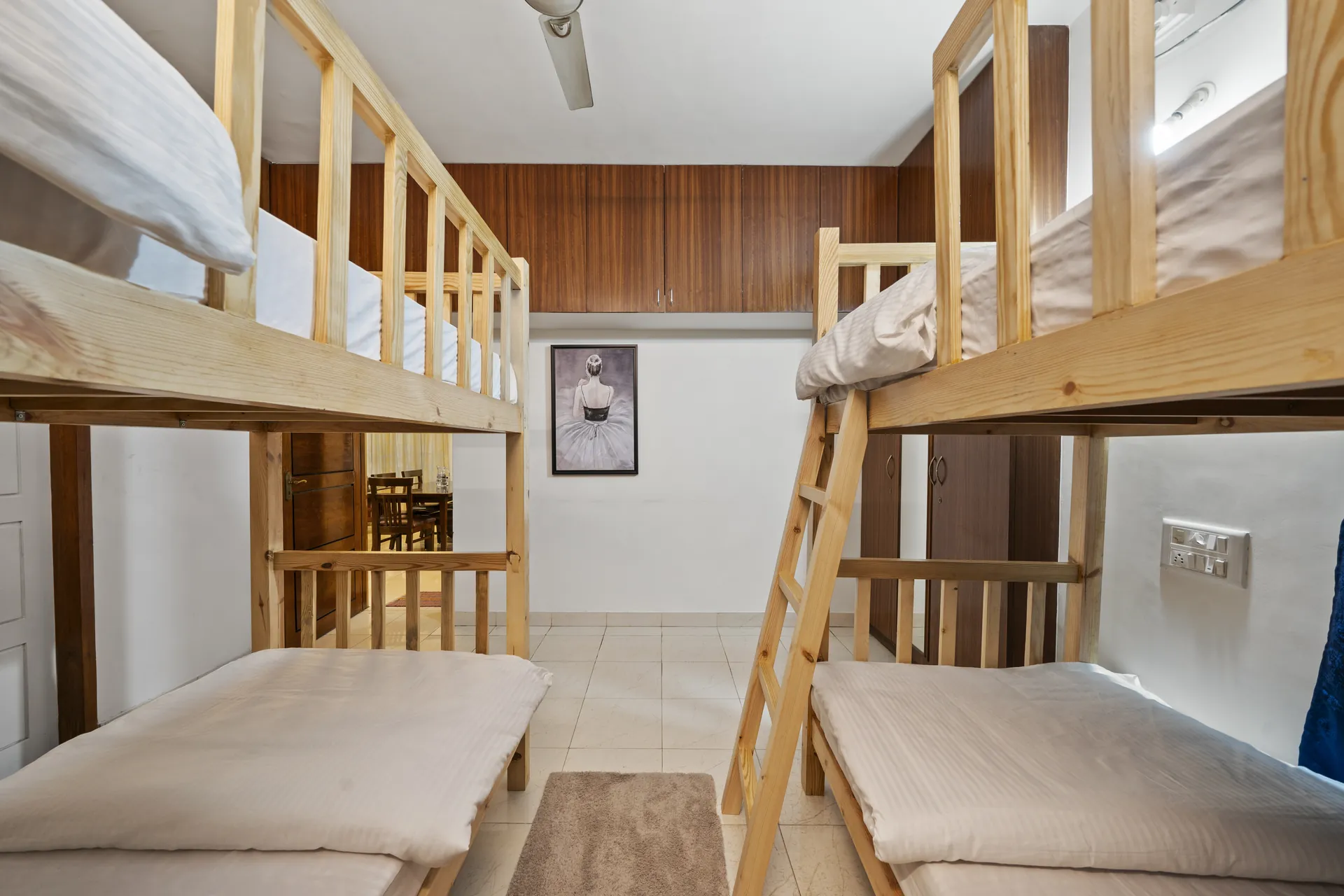 Bedroom with two wooden bunk beds, built-in wooden wardrobes, and a framed ballet photo on the wall.