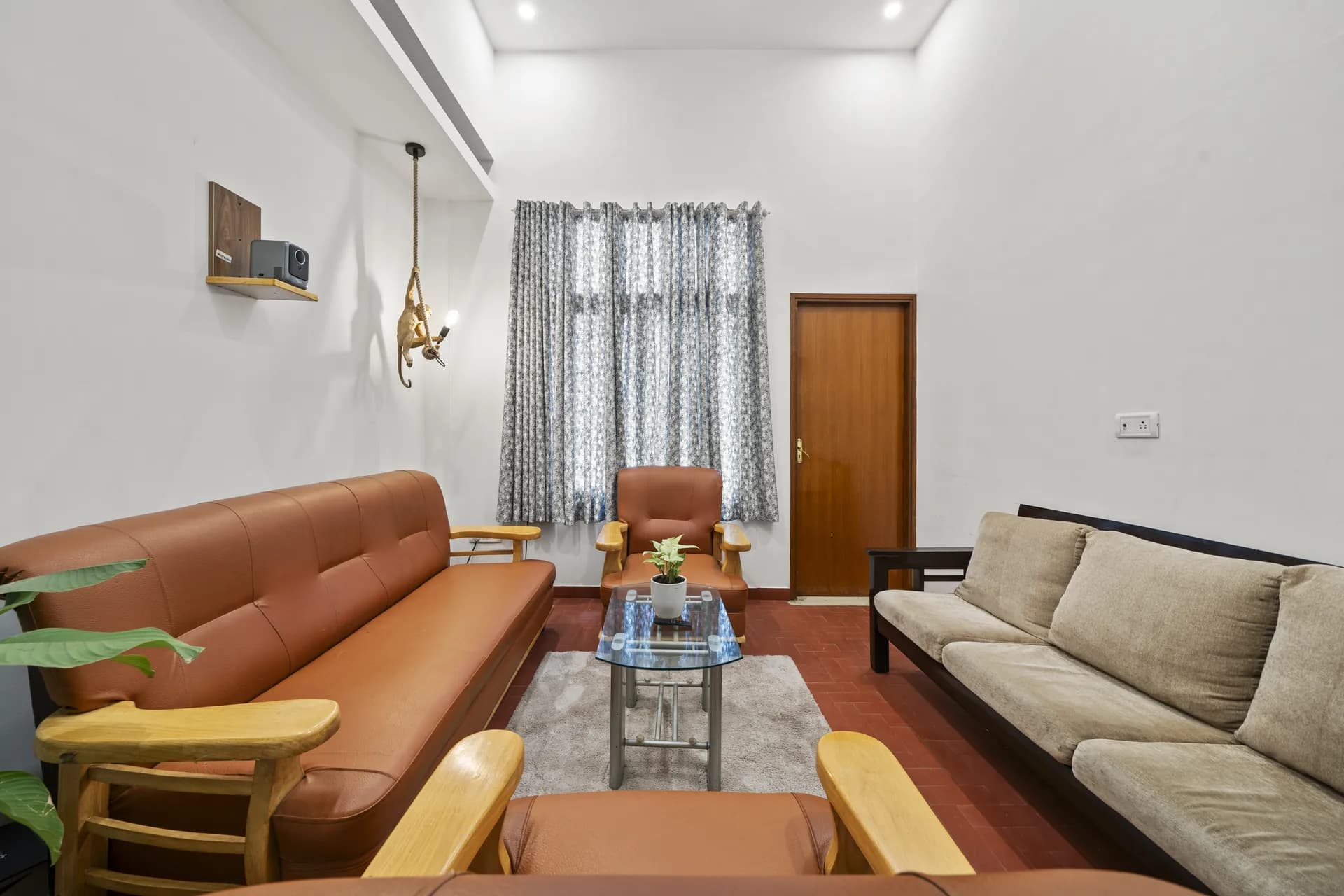Living room with tan leather sofa, grey fabric sofa, glass coffee table and monkey pendant light.