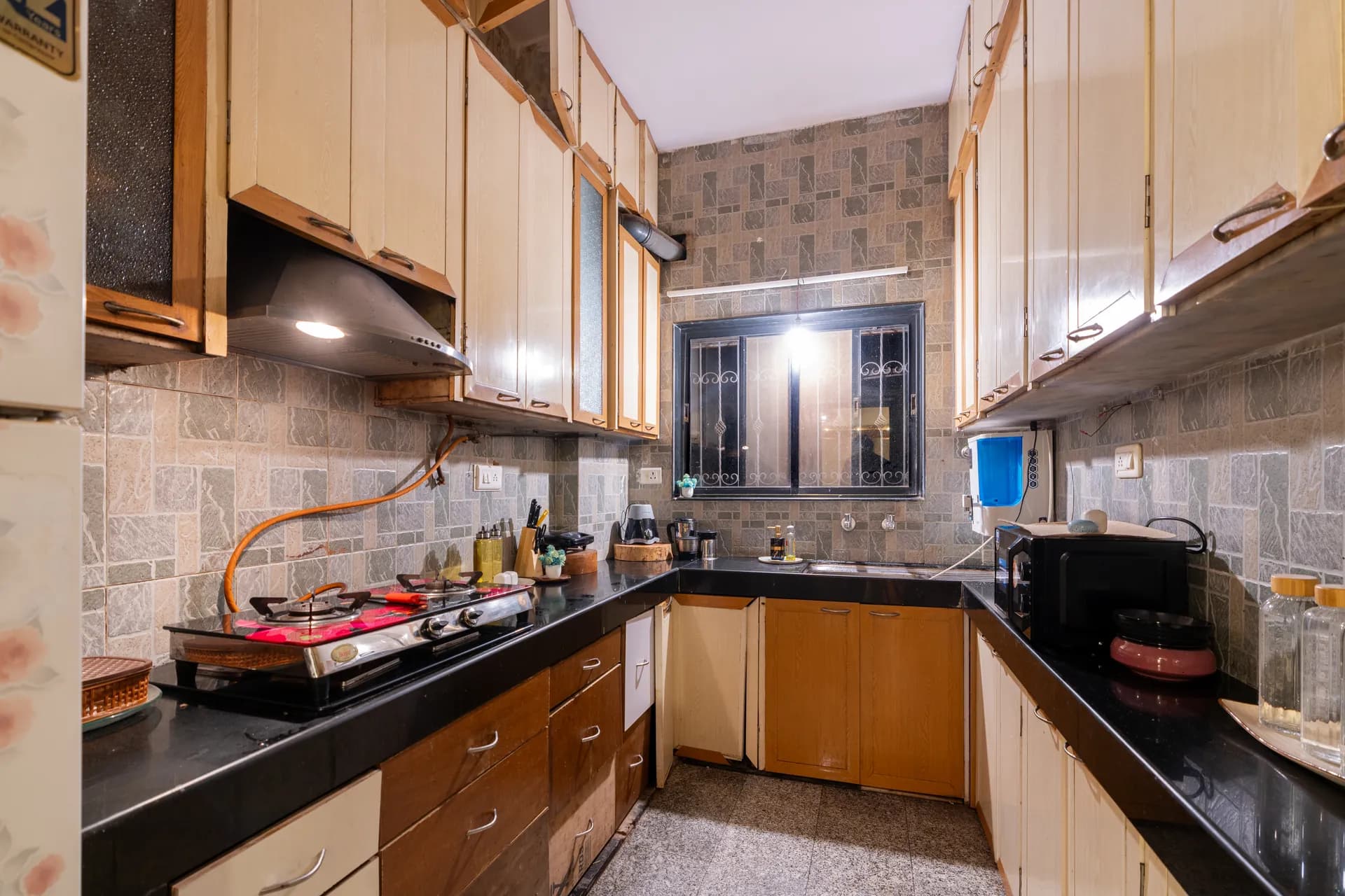 Galley kitchen with black countertops, a gas hob, wall cabinets and a microwave beside the sink.