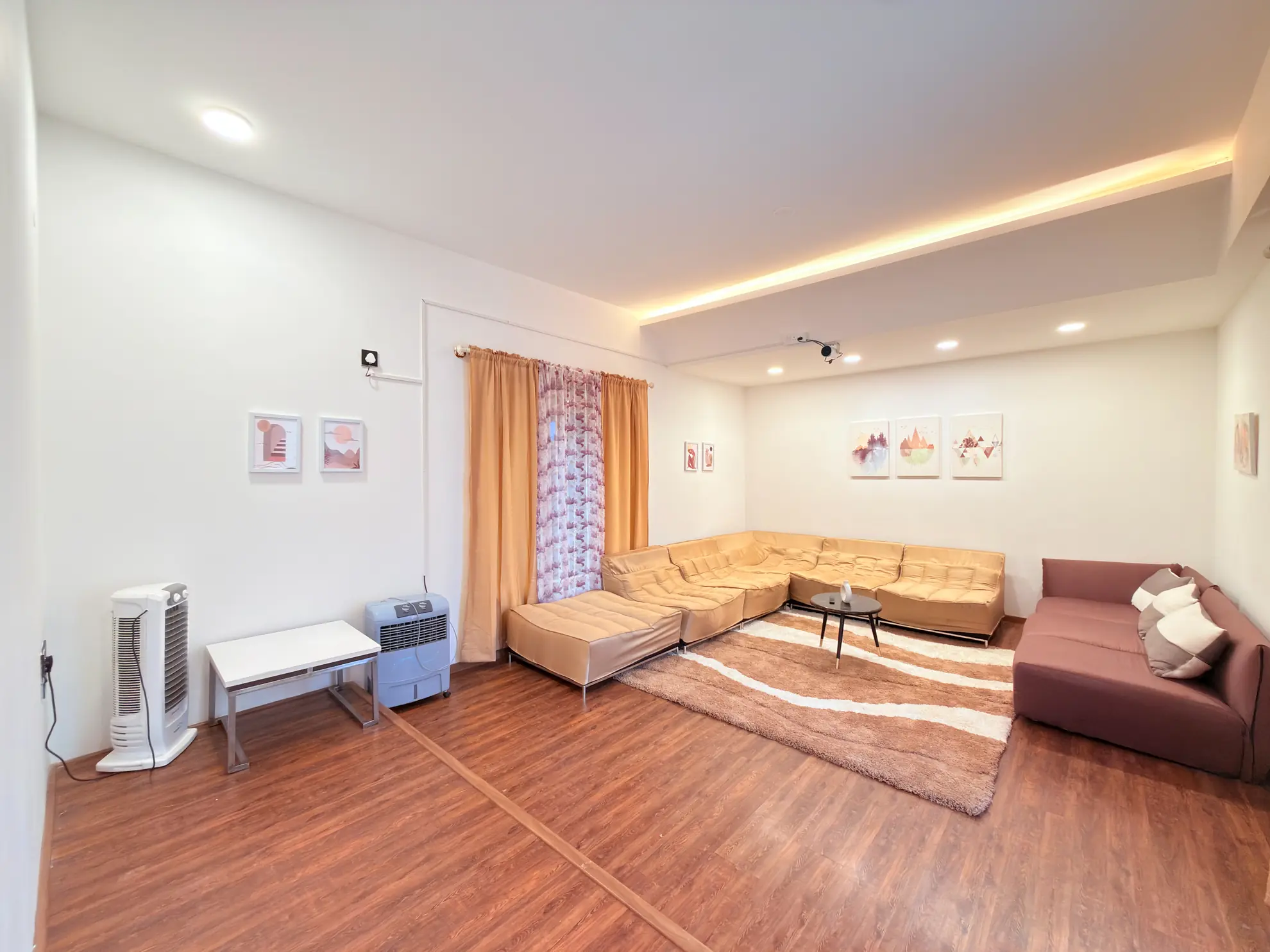Living room with a beige modular sofa, shag rug, and a wall-mounted light strip along the ceiling.