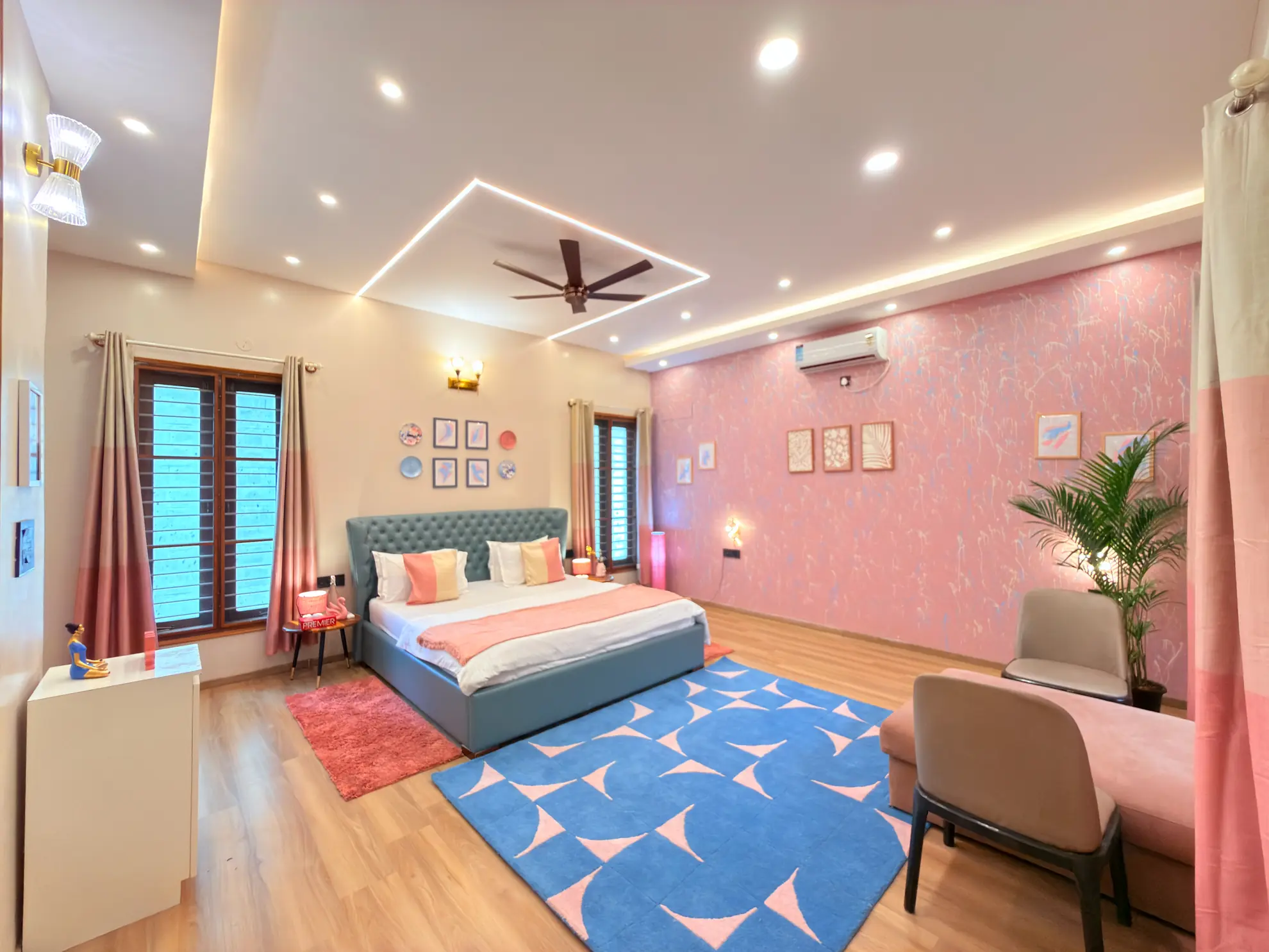 Bright bedroom with a teal upholstered bed, pink feature wall, blue geometric rug and built-in air conditioning.