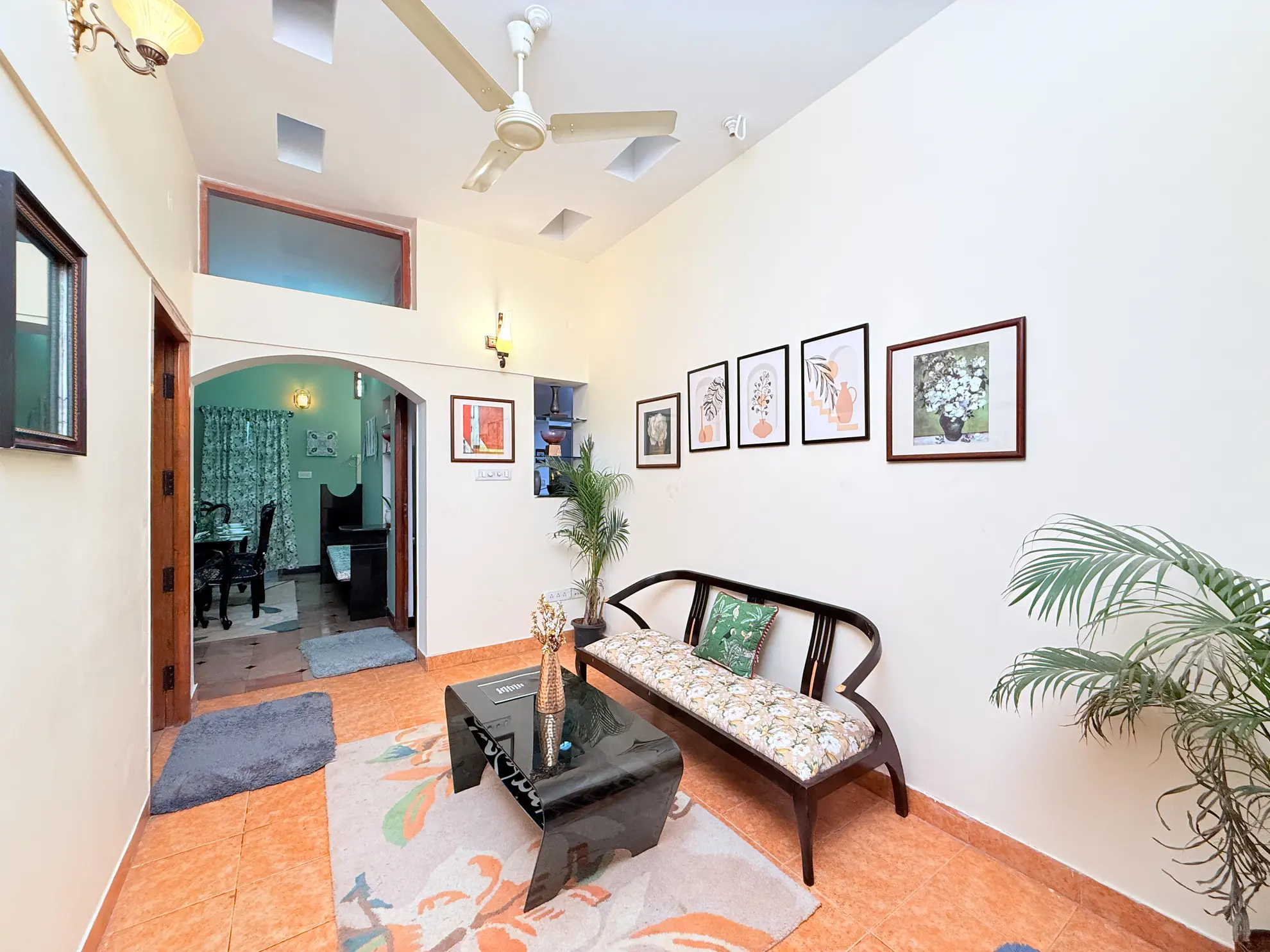 Bright foyer with a dark wood bench, black glass coffee table, and framed botanical prints on the wall.