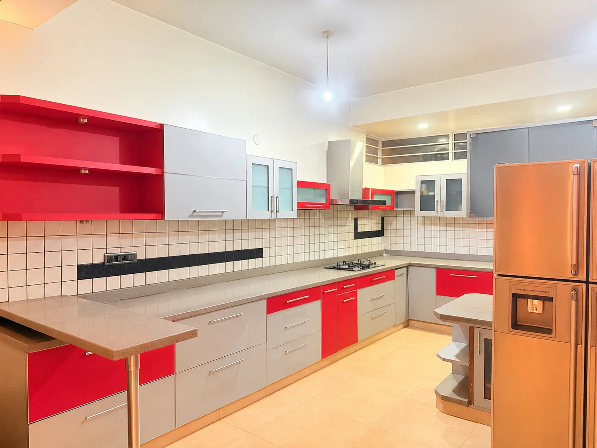 Kitchen with red and grey cabinets, gas hob, tiled backsplash and a stainless steel-look fridge freezer.